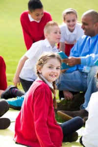 Children in Uniform sat outside with teacher