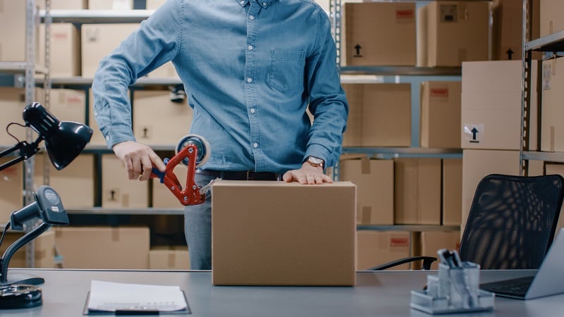 Person packing a box in a warehouse